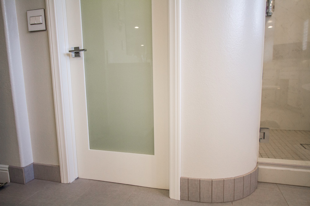 На фото: большая главная ванная комната в стиле неоклассика (современная классика) с плоскими фасадами, белыми фасадами, отдельно стоящей ванной, душем в нише, белыми стенами, полом из керамогранита, врезной раковиной, столешницей из известняка, бежевым полом и душем с распашными дверями