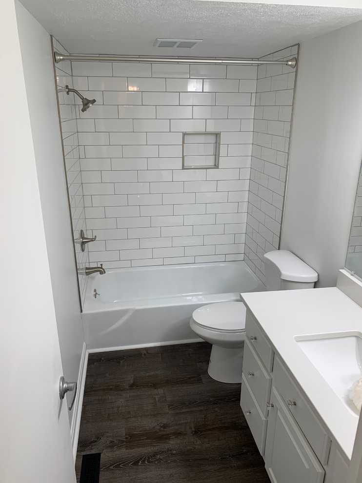 Idéer för mellanstora vintage vitt badrum med dusch, med luckor med upphöjd panel, vita skåp, ett badkar i en alkov, en dusch/badkar-kombination, vita väggar, mörkt trägolv, ett undermonterad handfat, bänkskiva i akrylsten, brunt golv och dusch med duschdraperi