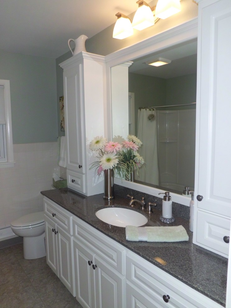 Пример оригинального дизайна: маленькая ванная комната с фасадами с выступающей филенкой, белыми фасадами, столешницей из гранита, душем над ванной, зелеными стенами, монолитной раковиной и белой плиткой для на участке и в саду