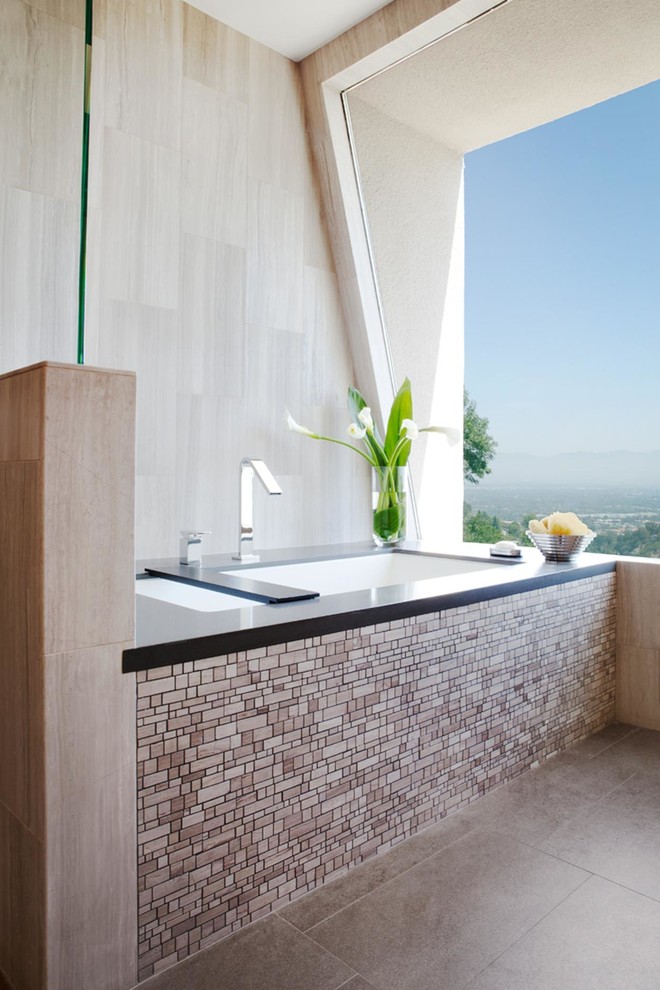 This is an example of a large contemporary ensuite bathroom in Los Angeles with a submerged sink, flat-panel cabinets, dark wood cabinets, grey tiles, white walls, a freestanding bath, a one-piece toilet, porcelain tiles, porcelain flooring, solid surface worktops and grey floors.