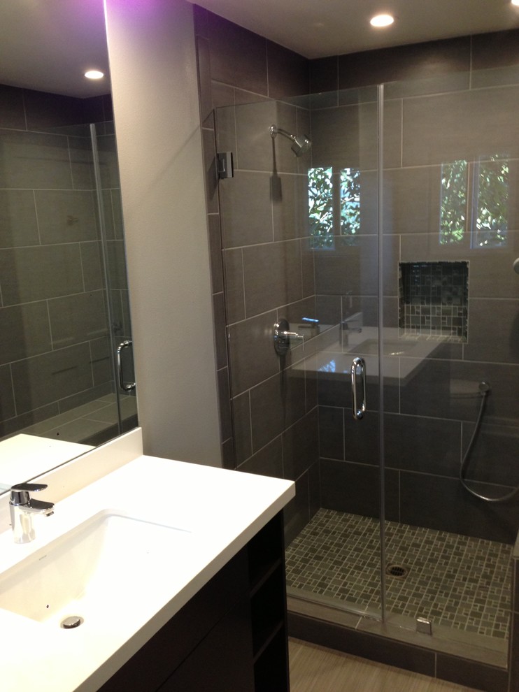 Inspiration for a mid-sized modern 3/4 gray tile and porcelain tile porcelain tile alcove shower remodel in Los Angeles with flat-panel cabinets, dark wood cabinets, gray walls, an undermount sink and solid surface countertops