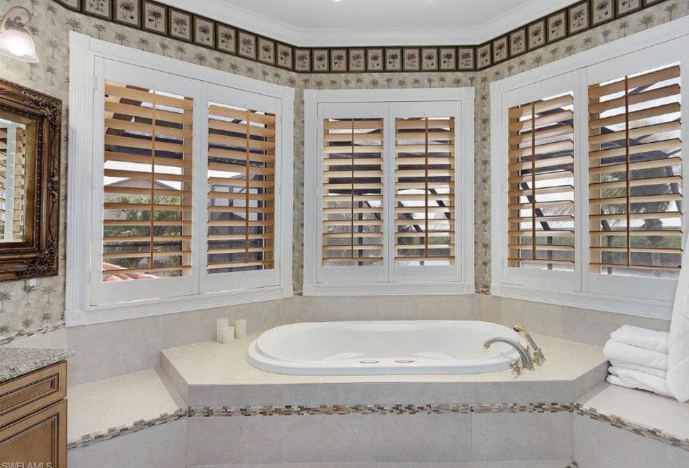 Inspiration för ett stort tropiskt beige beige en-suite badrum, med luckor med profilerade fronter, skåp i mellenmörkt trä, ett platsbyggt badkar, en dusch i en alkov, en toalettstol med separat cisternkåpa, beige kakel, travertinkakel, beige väggar, terrazzogolv, ett nedsänkt handfat, marmorbänkskiva, beiget golv och med dusch som är öppen