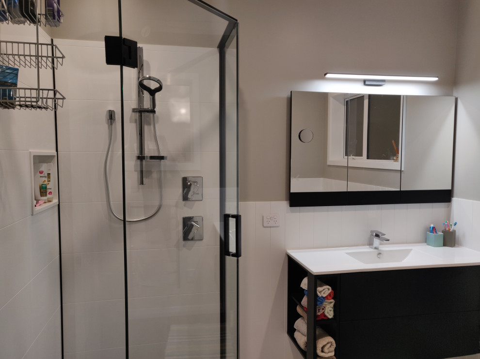 Idée de décoration pour une petite salle de bain design avec une baignoire d'angle, une douche d'angle, un mur gris, sol en stratifié, un sol gris et une cabine de douche à porte battante.