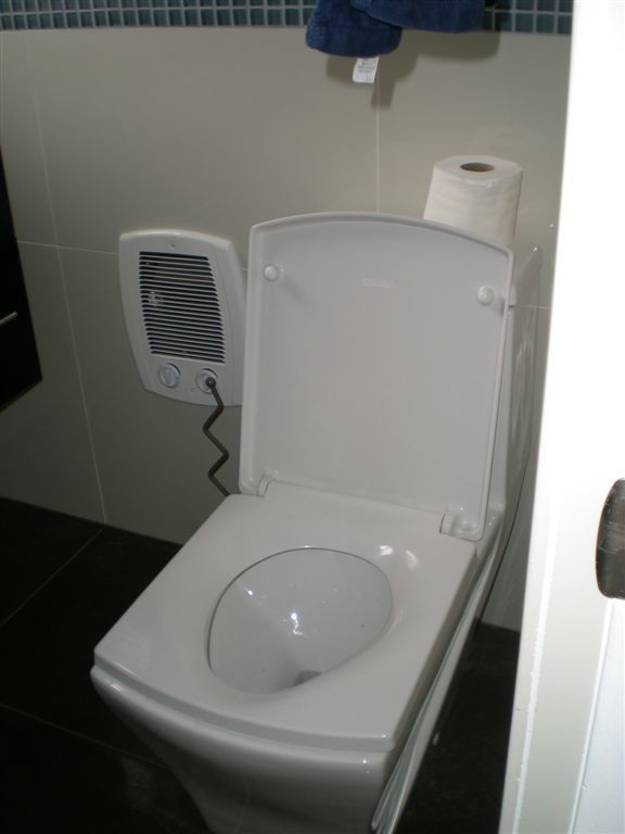 Cette photo montre une salle de bain moderne avec un placard à porte plane, des portes de placard noires, un plan de toilette en surface solide, un carrelage blanc, des carreaux de porcelaine et un sol en carrelage de porcelaine.