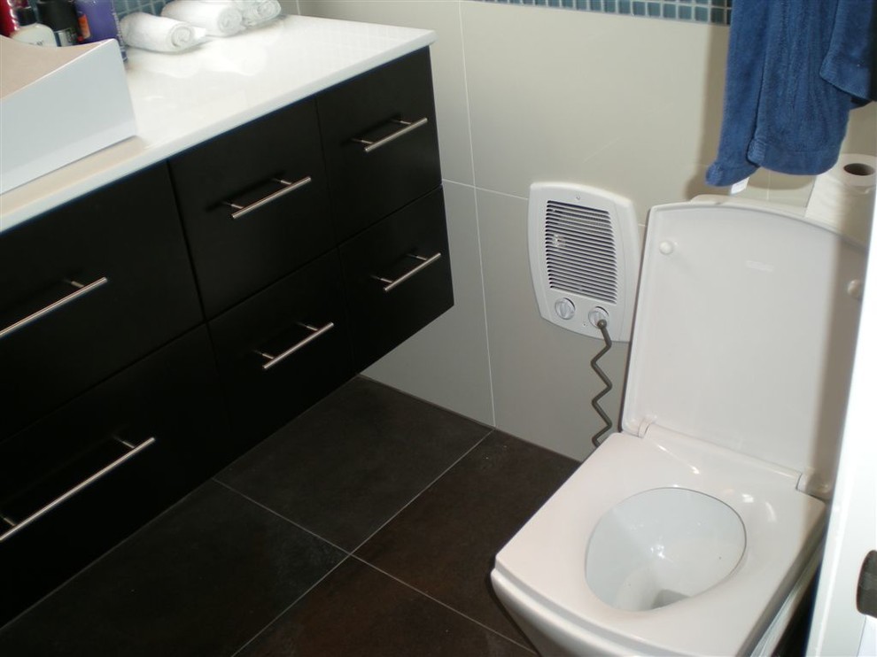 На фото: ванная комната в стиле модернизм с плоскими фасадами, черными фасадами, столешницей из искусственного камня, белой плиткой, керамогранитной плиткой и полом из керамогранита