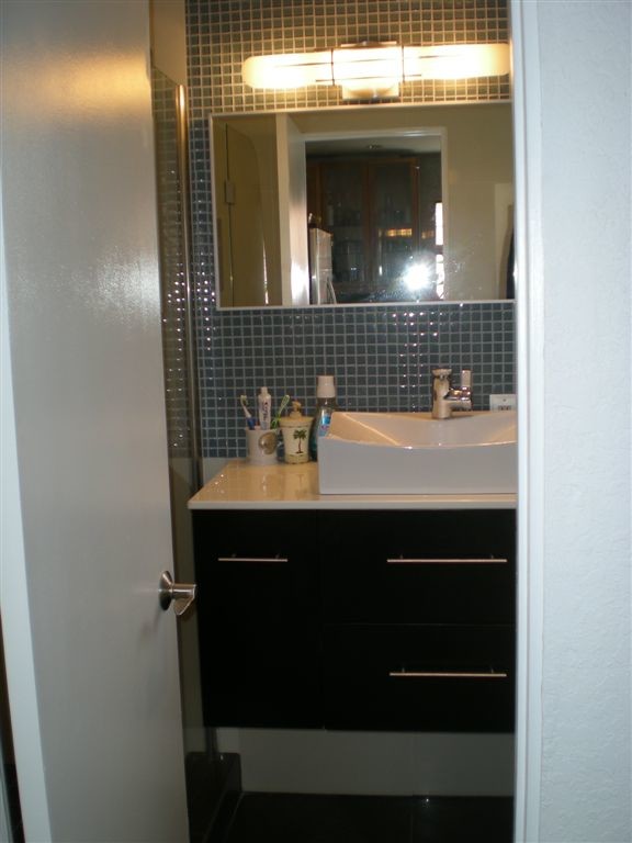 Ejemplo de cuarto de baño moderno con armarios con paneles lisos, puertas de armario negras, encimera de acrílico, baldosas y/o azulejos blancos, baldosas y/o azulejos de porcelana y suelo de baldosas de porcelana