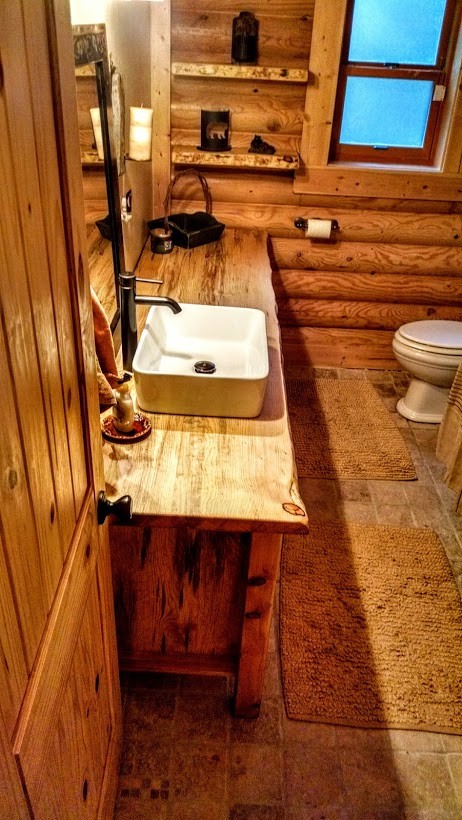 Rustik inredning av ett stort badrum, med möbel-liknande, skåp i slitet trä och träbänkskiva