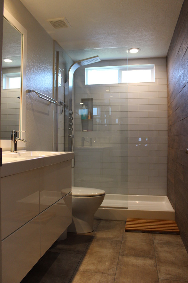 На фото: маленькая ванная комната в стиле модернизм с плоскими фасадами, белыми фасадами, открытым душем, раздельным унитазом, стеклянной плиткой, белыми стенами, душевой кабиной, монолитной раковиной, столешницей из искусственного камня и полом из керамогранита для на участке и в саду