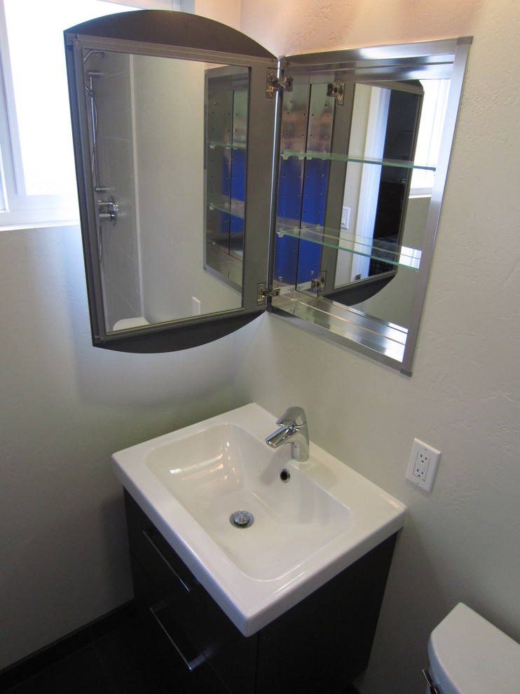 Kleines Modernes Badezimmer En Suite mit integriertem Waschbecken, flächenbündigen Schrankfronten, dunklen Holzschränken, Mineralwerkstoff-Waschtisch, Duschnische, Wandtoilette mit Spülkasten, beigen Fliesen, Porzellanfliesen, beiger Wandfarbe und Porzellan-Bodenfliesen in San Diego