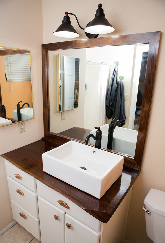 Modelo de cuarto de baño principal rústico de tamaño medio con armarios con paneles lisos, puertas de armario blancas, lavabo sobreencimera y encimera de madera