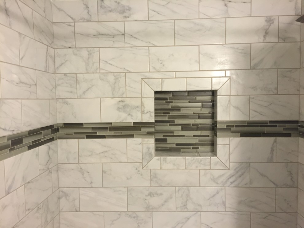 Inredning av ett litet badrum, med vita skåp, ett badkar i en alkov, en dusch i en alkov, en toalettstol med hel cisternkåpa, svart och vit kakel, glaskakel, grå väggar, klinkergolv i keramik, ett nedsänkt handfat och granitbänkskiva
