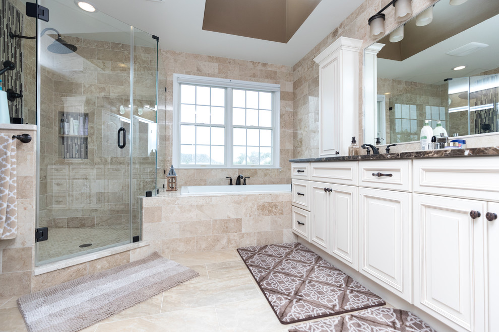 Large traditional ensuite bathroom in DC Metro with raised-panel cabinets, white cabinets, a built-in bath, a corner shower, beige tiles, stone tiles, porcelain flooring, a submerged sink, granite worktops, beige floors and a hinged door.
