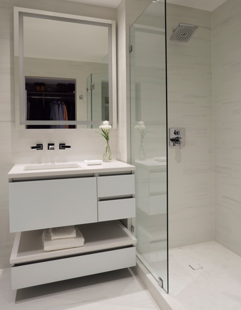 Стильный дизайн: маленькая главная ванная комната в стиле модернизм с стеклянными фасадами, белыми фасадами, душем в нише, белой плиткой, керамогранитной плиткой, белыми стенами, полом из керамогранита, столешницей из искусственного кварца, белым полом, душем с распашными дверями, белой столешницей, нишей, тумбой под одну раковину и подвесной тумбой для на участке и в саду - последний тренд