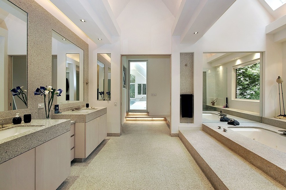 На фото: огромная главная ванная комната в современном стиле с плоскими фасадами, бежевыми фасадами, полновстраиваемой ванной, бежевой плиткой, коричневой плиткой, плиткой из известняка, белыми стенами, полом из известняка, врезной раковиной, столешницей из известняка, разноцветным полом и разноцветной столешницей с