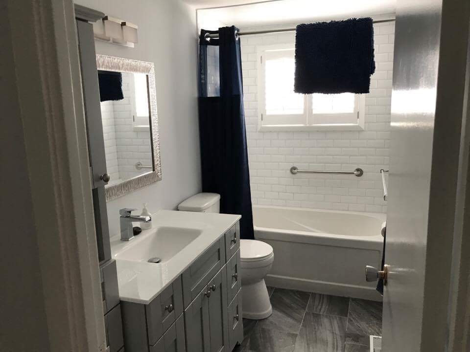 Bild på ett litet funkis vit vitt badrum med dusch, med möbel-liknande, grå skåp, ett platsbyggt badkar, en dusch/badkar-kombination, vit kakel, keramikplattor, grå väggar, klinkergolv i porslin, marmorbänkskiva och svart golv