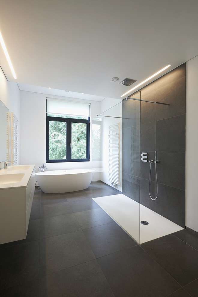 Idéer för mellanstora funkis en-suite badrum, med släta luckor, vita skåp, ett fristående badkar, en kantlös dusch, skifferkakel, vita väggar, skiffergolv, ett integrerad handfat, bänkskiva i akrylsten, svart golv och med dusch som är öppen