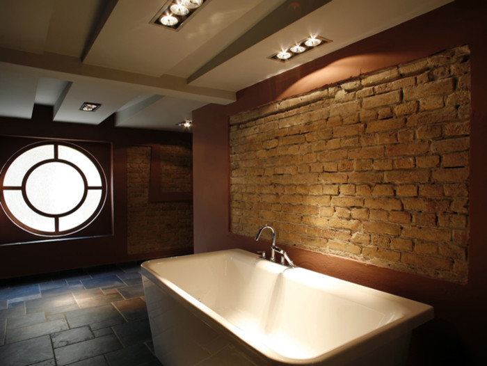 Immagine di un'ampia stanza da bagno padronale minimal con vasca freestanding, pavimento in ardesia, pavimento grigio, travi a vista e pareti in mattoni