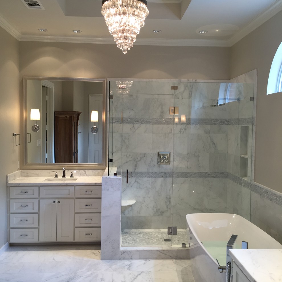 Photo of a large modern ensuite bathroom in Dallas with a submerged sink, shaker cabinets, white cabinets, marble worktops, a freestanding bath, a corner shower, a one-piece toilet, white tiles, stone tiles, white walls, marble flooring and grey floors.