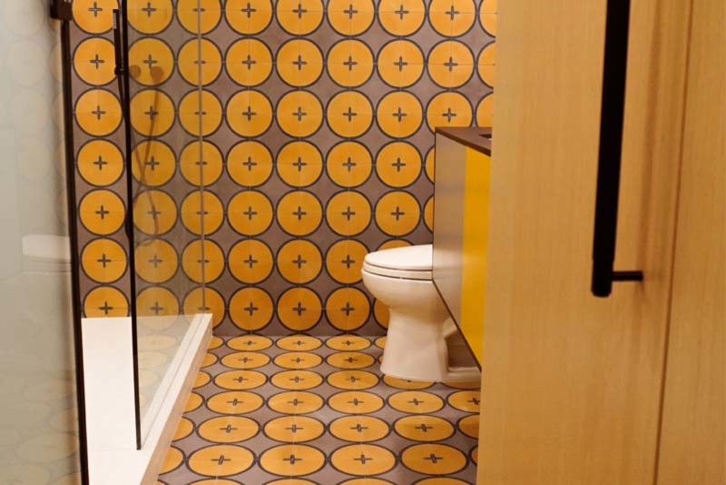 Свежая идея для дизайна: ванная комната среднего размера в стиле модернизм с плоскими фасадами, оранжевыми фасадами, душем в нише, раздельным унитазом, оранжевой плиткой, керамической плиткой, оранжевыми стенами, полом из керамической плитки, душевой кабиной, накладной раковиной, оранжевым полом, душем с распашными дверями, столешницей из искусственного кварца, черной столешницей, нишей, тумбой под одну раковину и встроенной тумбой - отличное фото интерьера