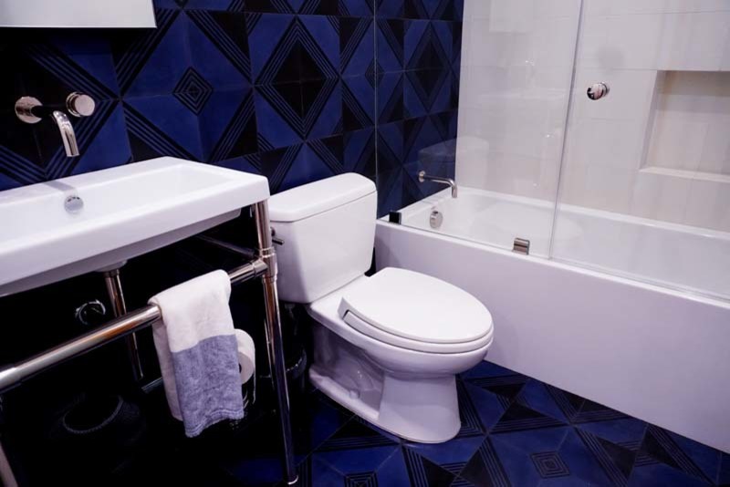 Exempel på ett mellanstort modernt vit vitt badrum med dusch, med ett badkar i en alkov, en dusch/badkar-kombination, en toalettstol med separat cisternkåpa, blå kakel, keramikplattor, blå väggar, blått golv, dusch med gångjärnsdörr, klinkergolv i keramik, vita skåp, ett fristående handfat och bänkskiva i kvarts