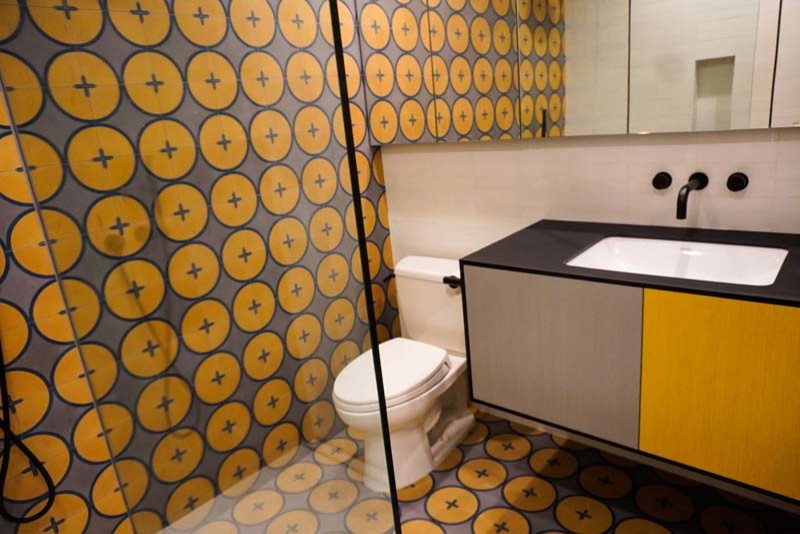 Источник вдохновения для домашнего уюта: ванная комната среднего размера в стиле модернизм с плоскими фасадами, оранжевыми фасадами, угловым душем, раздельным унитазом, оранжевой плиткой, керамической плиткой, оранжевыми стенами, полом из керамической плитки, душевой кабиной, накладной раковиной, столешницей из искусственного кварца, оранжевым полом, душем с распашными дверями, черной столешницей, нишей, тумбой под одну раковину и встроенной тумбой