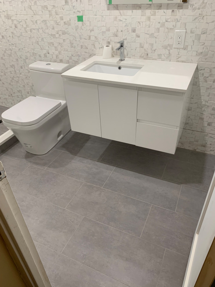 Design ideas for a medium sized modern ensuite bathroom in New York with flat-panel cabinets, white cabinets, a walk-in shower, a one-piece toilet, white tiles, porcelain tiles, grey walls, porcelain flooring, a submerged sink, engineered stone worktops, grey floors, a hinged door, white worktops, a wall niche, a single sink and a floating vanity unit.