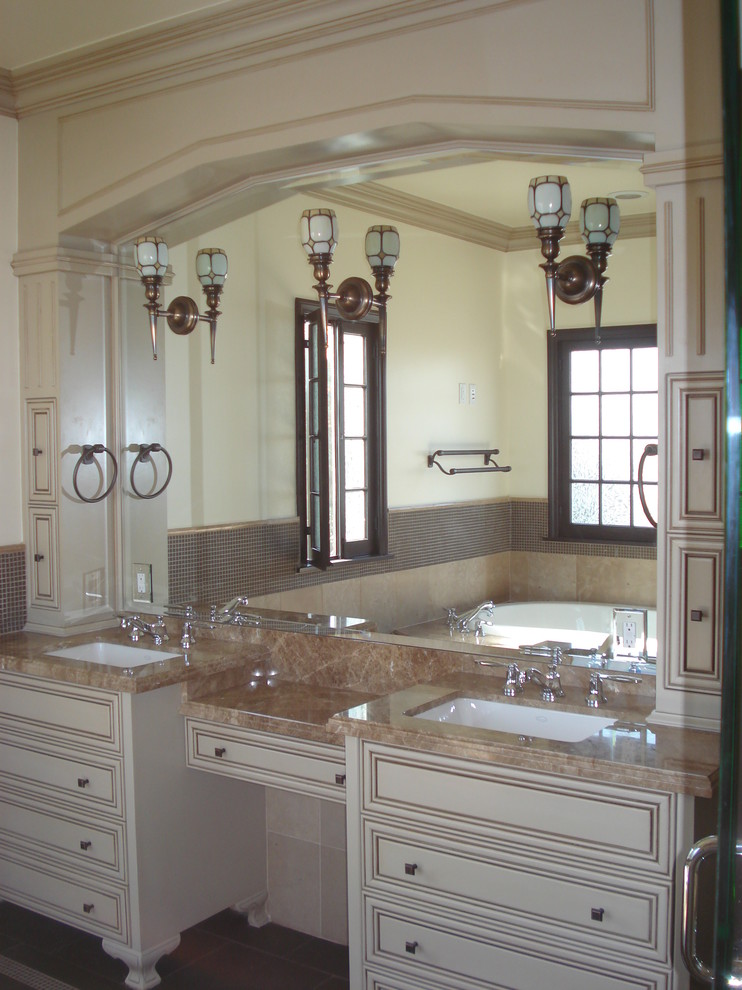 На фото: большая главная ванная комната в средиземноморском стиле с плоскими фасадами, бежевыми фасадами, угловой ванной, бежевой плиткой, керамогранитной плиткой, бежевыми стенами, врезной раковиной и коричневым полом