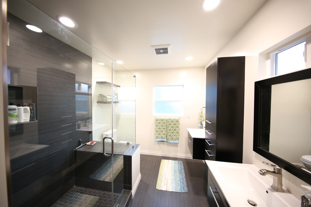 Foto de cuarto de baño actual con armarios con paneles lisos, puertas de armario negras, ducha esquinera, paredes blancas y lavabo integrado