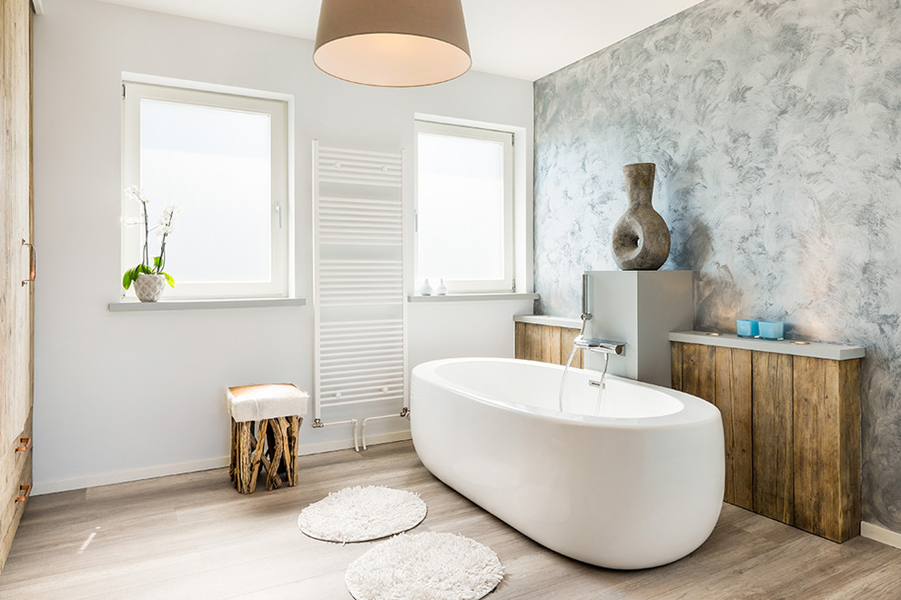 Ispirazione per una stanza da bagno design con vasca freestanding, pareti grigie, pavimento in legno massello medio e pavimento marrone