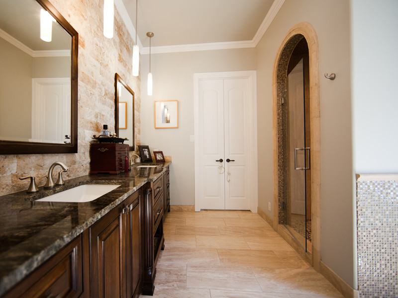 Mid-sized trendy beige tile and stone tile travertine floor and beige floor double shower photo in Dallas with an undermount sink, furniture-like cabinets, dark wood cabinets, granite countertops, a two-piece toilet, beige walls and a hinged shower door