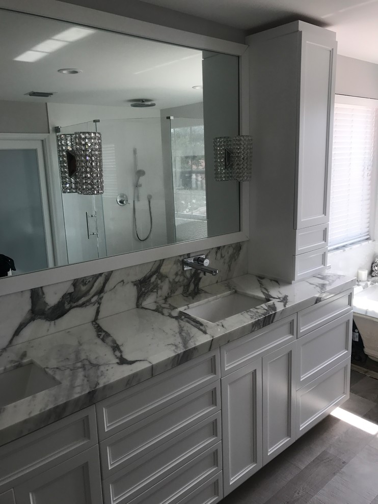 Photo of a large classic ensuite bathroom in Miami with shaker cabinets, white cabinets, a submerged bath, a corner shower, black and white tiles, grey tiles, stone slabs, grey walls, medium hardwood flooring, a submerged sink, marble worktops, brown floors and a hinged door.