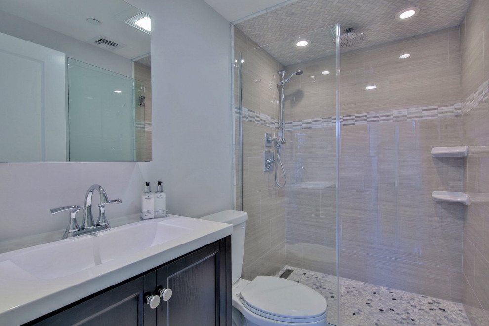 Inspiration for a mid-sized transitional beige tile, gray tile, white tile and porcelain tile pebble tile floor and multicolored floor alcove shower remodel in Chicago with recessed-panel cabinets, gray cabinets, a two-piece toilet, gray walls, an integrated sink, quartz countertops, a hinged shower door and white countertops