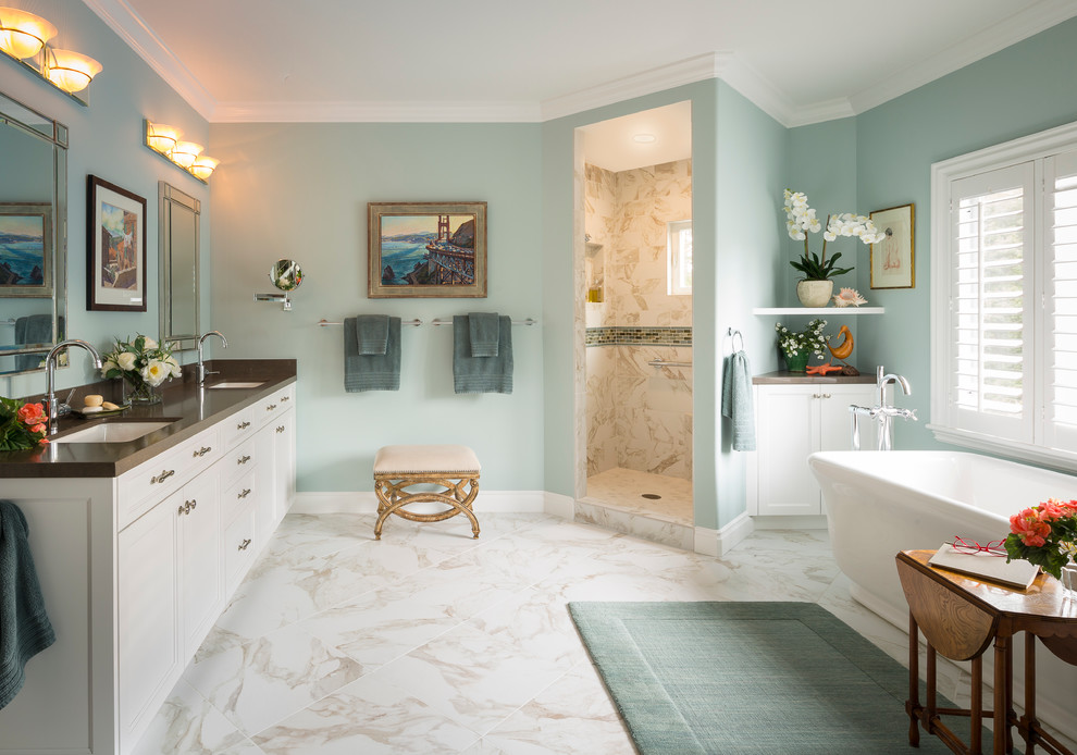 На фото: ванная комната в классическом стиле с белыми фасадами, отдельно стоящей ванной, угловым душем и синими стенами с