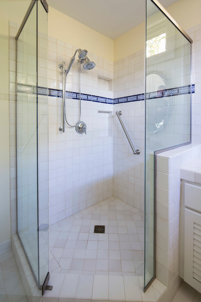 Foto på ett vintage badrum, med luckor med lamellpanel, vita skåp, en dusch i en alkov, vit kakel, keramikplattor, gula väggar, klinkergolv i keramik, ett nedsänkt handfat, kaklad bänkskiva, beiget golv och dusch med gångjärnsdörr