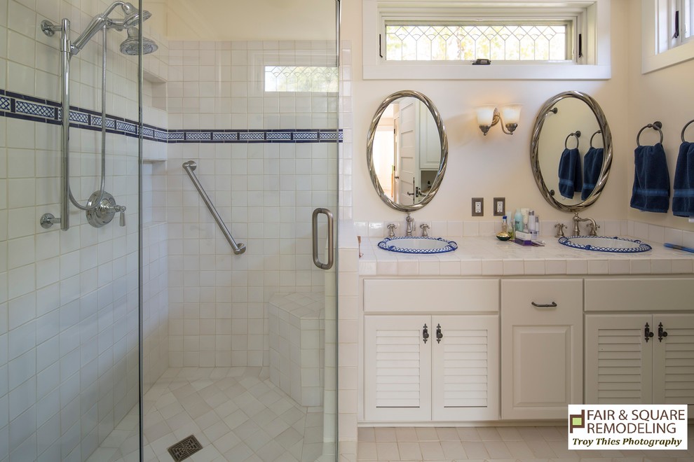 Klassisk inredning av ett badrum, med luckor med lamellpanel, vita skåp, en dusch i en alkov, vit kakel, keramikplattor, gula väggar, klinkergolv i keramik, ett nedsänkt handfat, kaklad bänkskiva, beiget golv och dusch med gångjärnsdörr