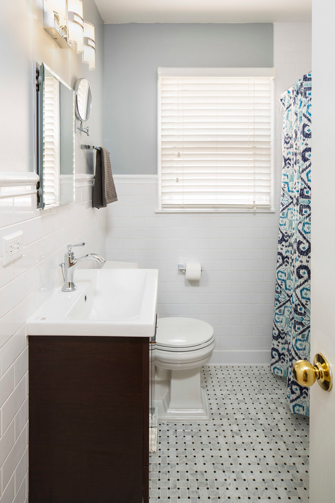 Klassisches Badezimmer mit dunklen Holzschränken, Duschbadewanne, Wandtoilette mit Spülkasten, weißen Fliesen, Metrofliesen, blauer Wandfarbe, integriertem Waschbecken und Duschvorhang-Duschabtrennung in Minneapolis