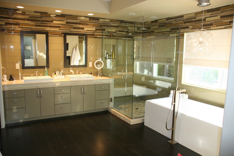 Пример оригинального дизайна: главная ванная комната среднего размера в современном стиле с плоскими фасадами, бежевыми фасадами, отдельно стоящей ванной, угловым душем, бежевой плиткой, стеклянной плиткой, бежевыми стенами, полом из керамогранита, накладной раковиной, столешницей из бетона, черным полом, душем с распашными дверями и бежевой столешницей