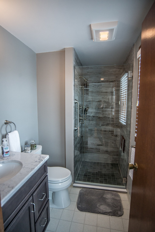 Small classic ensuite bathroom in New York with recessed-panel cabinets, grey cabinets, an alcove shower, a one-piece toilet, beige tiles, marble tiles, grey walls, a built-in sink, granite worktops and a hinged door.