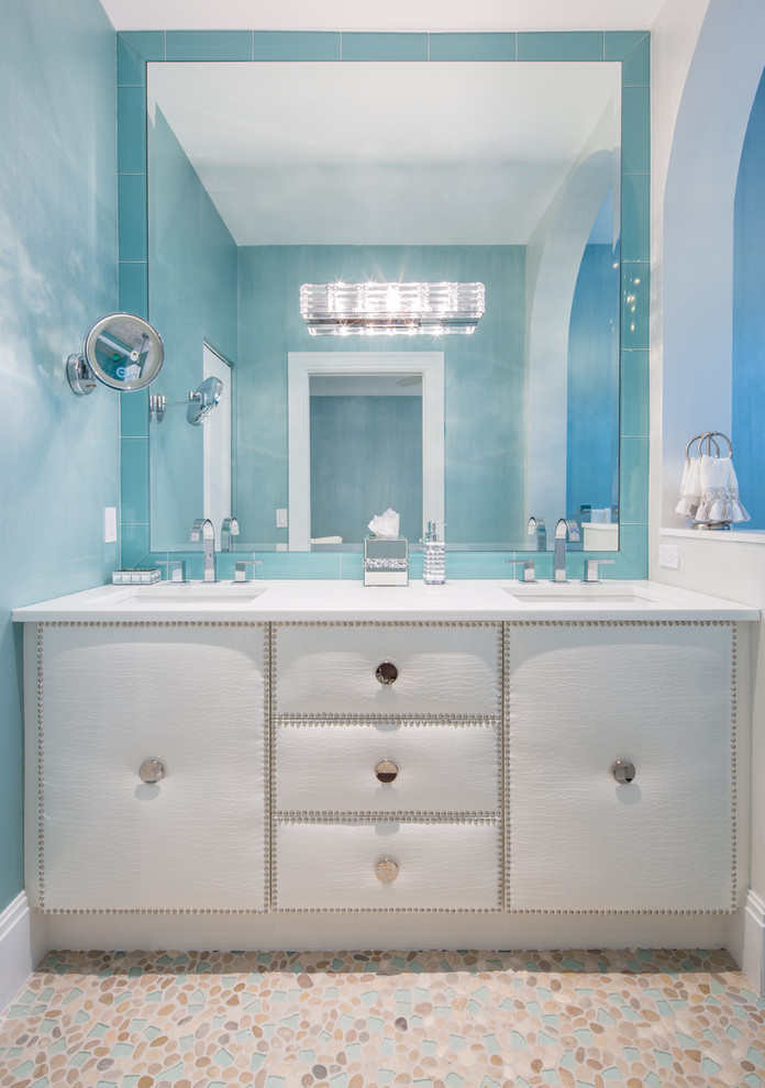 マイアミにあるビーチスタイルのおしゃれな浴室 (アンダーカウンター洗面器、白いキャビネット、青いタイル、ガラスタイル、青い壁、玉石タイル) の写真