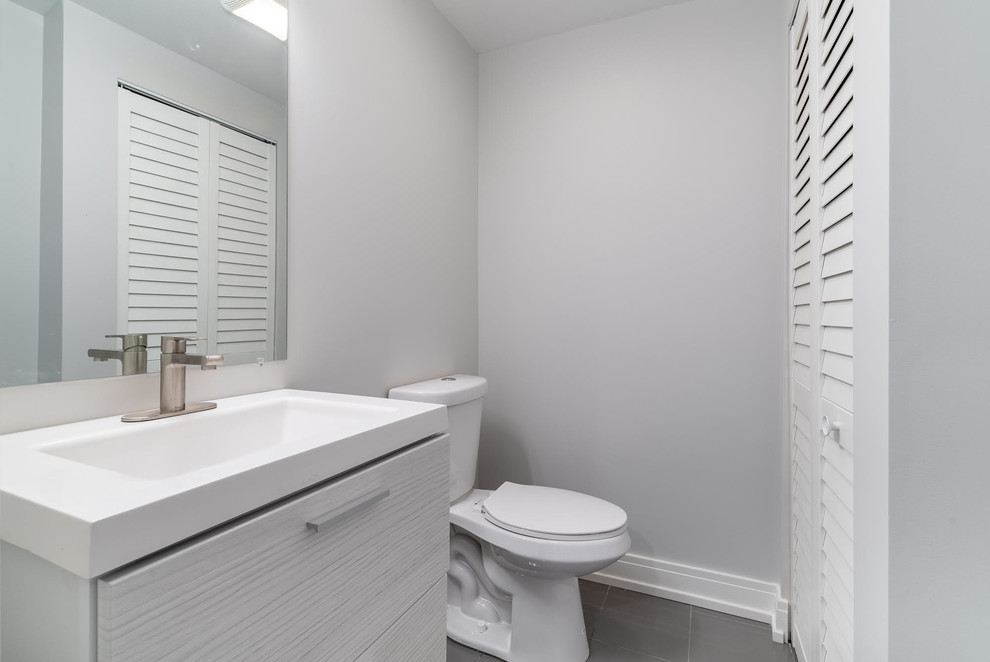 Пример оригинального дизайна: ванная комната среднего размера в современном стиле с плоскими фасадами, серыми фасадами, раздельным унитазом, серыми стенами, полом из керамогранита, душевой кабиной, монолитной раковиной, столешницей из искусственного кварца, серым полом и белой столешницей