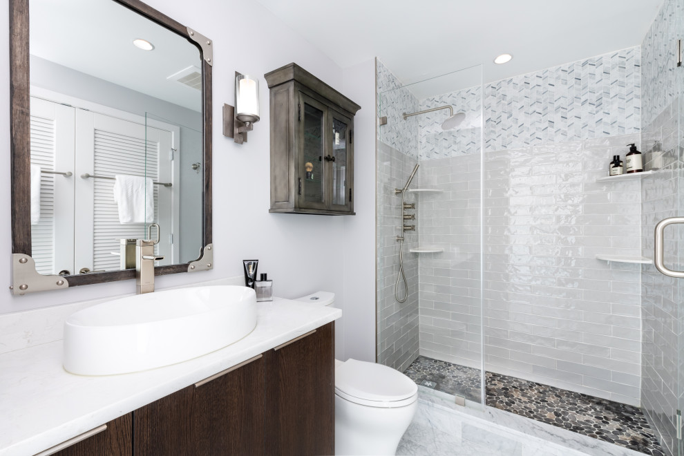 Bild på ett vintage vit vitt badrum med dusch, med släta luckor, skåp i mörkt trä, en dusch i en alkov, grå kakel, tunnelbanekakel, vita väggar, ett fristående handfat och vitt golv