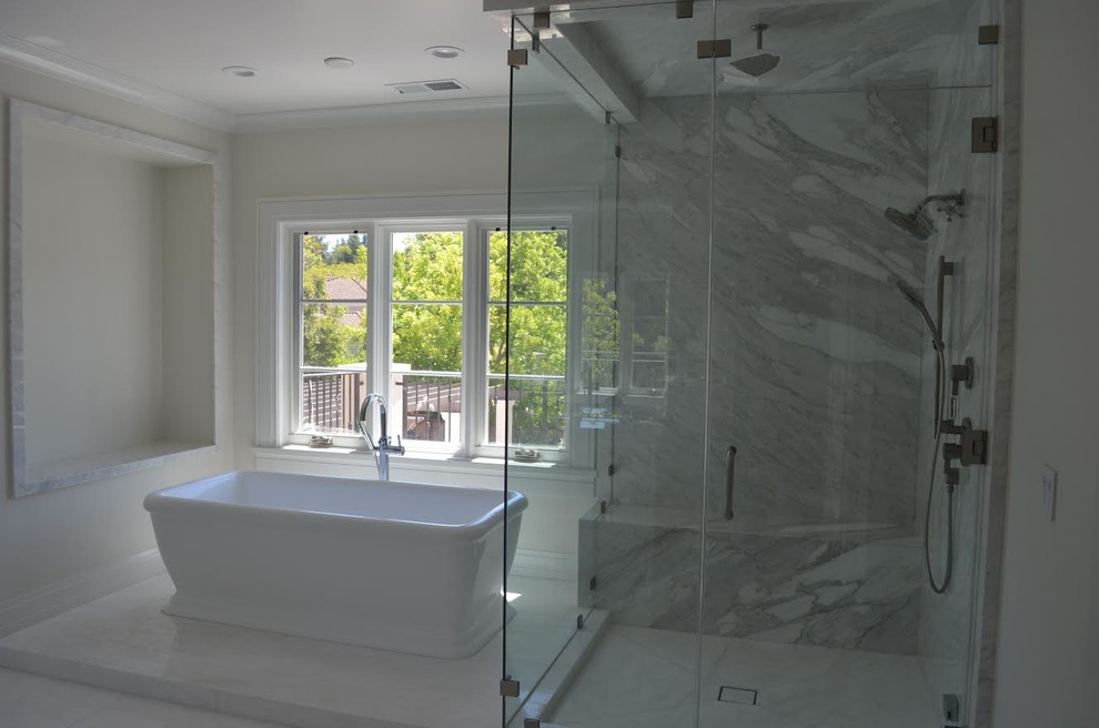 Klassisk inredning av ett stort en-suite badrum, med luckor med profilerade fronter, vita skåp, ett fristående badkar, en hörndusch, marmorkakel, beige väggar, marmorgolv, ett undermonterad handfat, marmorbänkskiva, vitt golv och dusch med gångjärnsdörr