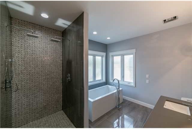 Medium sized contemporary ensuite bathroom in Edmonton with a freestanding bath, an alcove shower, a two-piece toilet, beige walls, vinyl flooring, a submerged sink and concrete worktops.