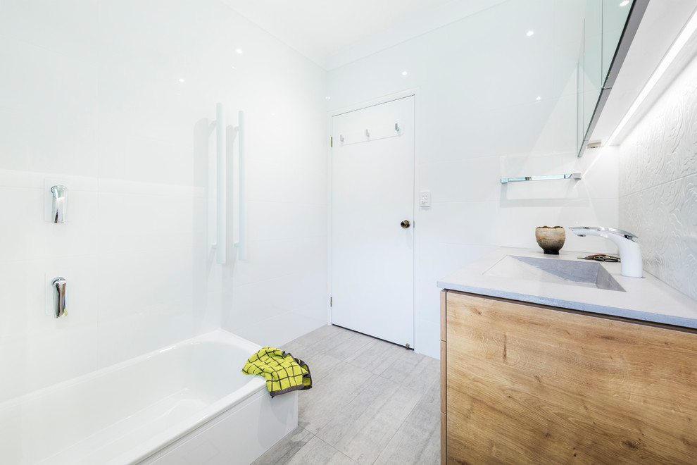 Idée de décoration pour une petite salle de bain principale minimaliste en bois clair avec un placard en trompe-l'oeil, une baignoire posée, un combiné douche/baignoire, WC séparés, un carrelage blanc, des carreaux de céramique, un mur blanc, un sol en carrelage de céramique, un lavabo intégré, un plan de toilette en béton, un sol gris et une cabine de douche à porte battante.