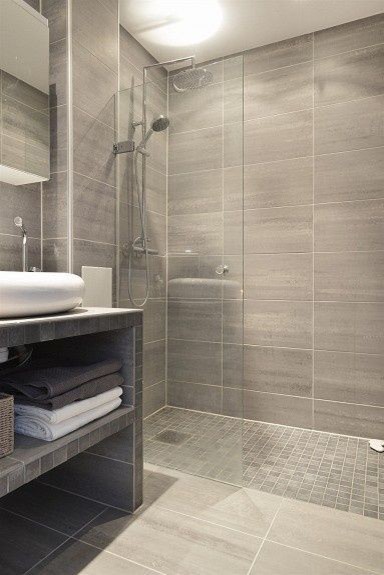 Idéer för att renovera ett mellanstort funkis badrum med dusch, med öppna hyllor, grå skåp, en kantlös dusch, grå kakel, grå väggar, porslinskakel, klinkergolv i porslin, ett fristående handfat, kaklad bänkskiva, grått golv och med dusch som är öppen