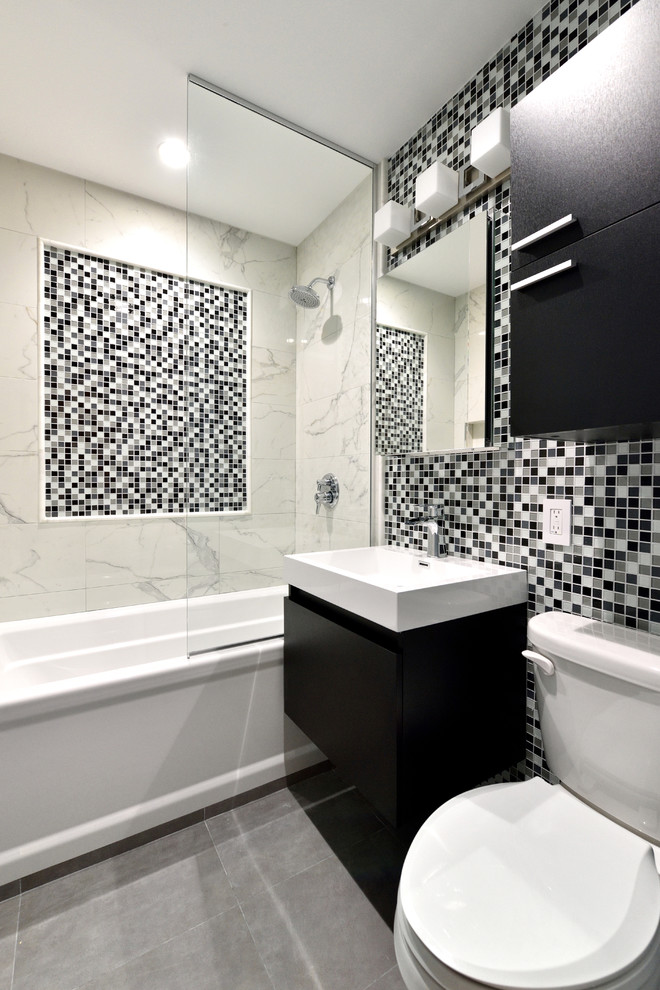 Ejemplo de cuarto de baño contemporáneo de tamaño medio con bañera empotrada, combinación de ducha y bañera, sanitario de dos piezas, baldosas y/o azulejos blancas y negros, baldosas y/o azulejos de porcelana, paredes grises, suelo de pizarra y lavabo integrado