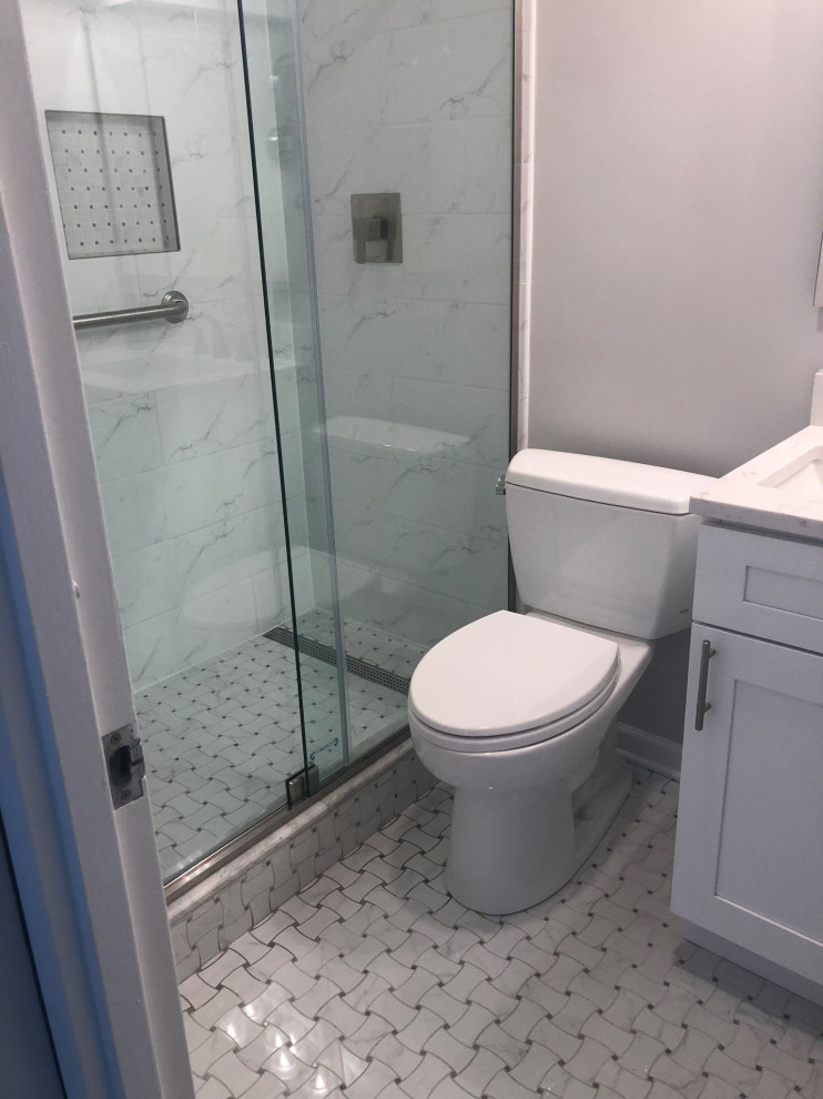 На фото: маленькая ванная комната в стиле неоклассика (современная классика) с фасадами в стиле шейкер, белыми фасадами, душем в нише, раздельным унитазом, серой плиткой, мраморной плиткой, белыми стенами, полом из керамогранита, душевой кабиной, врезной раковиной, разноцветным полом, душем с раздвижными дверями, белой столешницей, нишей, тумбой под одну раковину и встроенной тумбой для на участке и в саду