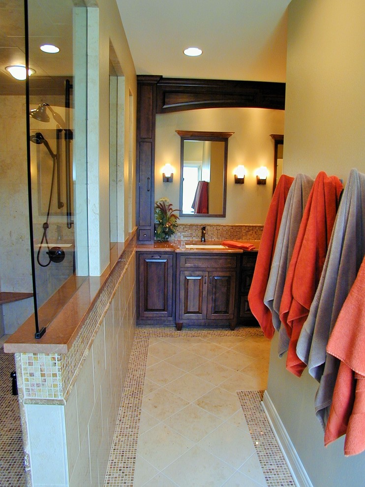 Walk-in shower - traditional multicolored tile and stone tile mosaic tile floor walk-in shower idea in Milwaukee with an undermount sink, raised-panel cabinets, dark wood cabinets, granite countertops, a two-piece toilet and beige walls