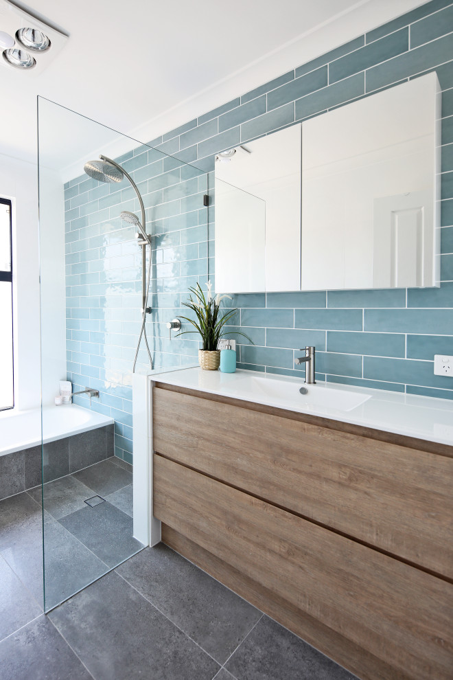 Идея дизайна: ванная комната в морском стиле с плоскими фасадами, фасадами цвета дерева среднего тона, ванной в нише, душевой комнатой, синей плиткой, монолитной раковиной, серым полом, открытым душем и белой столешницей