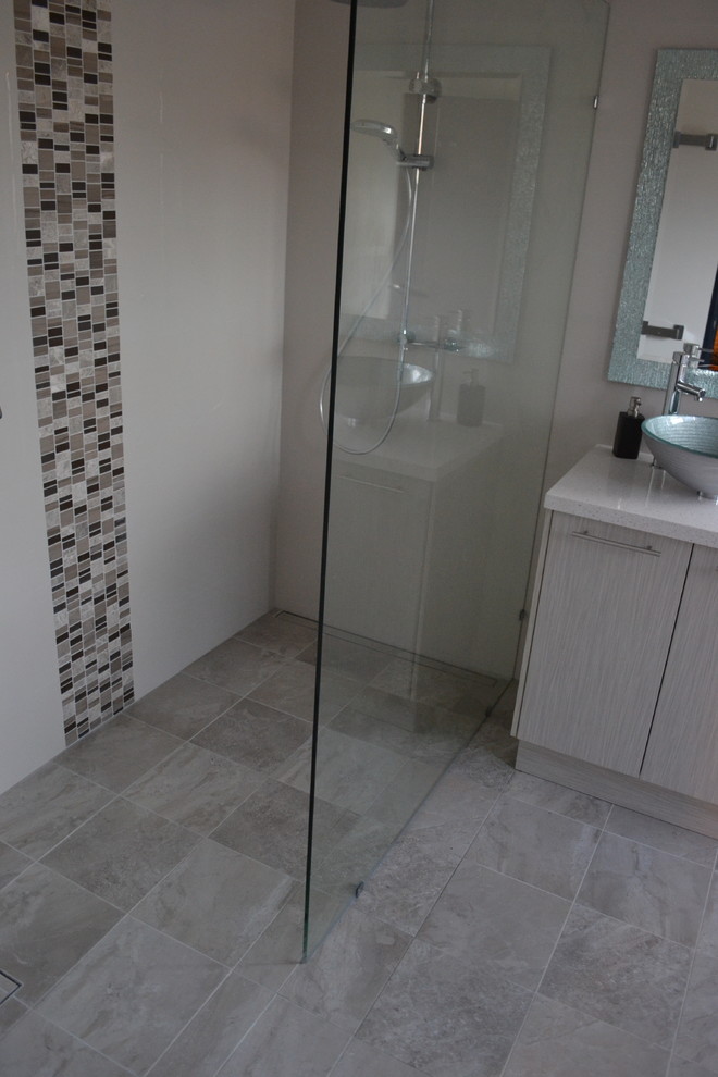 Idéer för att renovera ett mellanstort funkis en-suite badrum, med ett fristående handfat, grå skåp, granitbänkskiva, en öppen dusch, en toalettstol med hel cisternkåpa, grå kakel, porslinskakel, grå väggar och klinkergolv i porslin